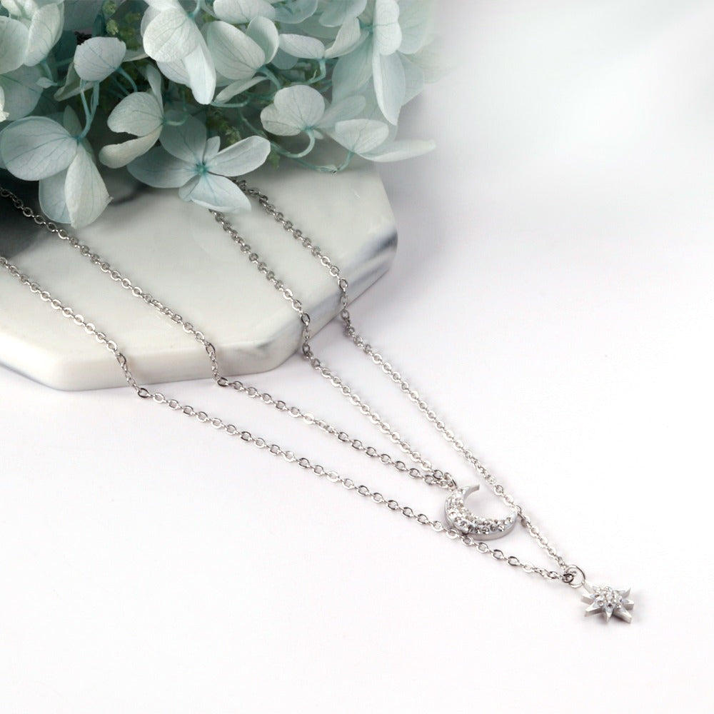 Double layered silver necklace with moon pendant in inner chain and star pendant in outer chain