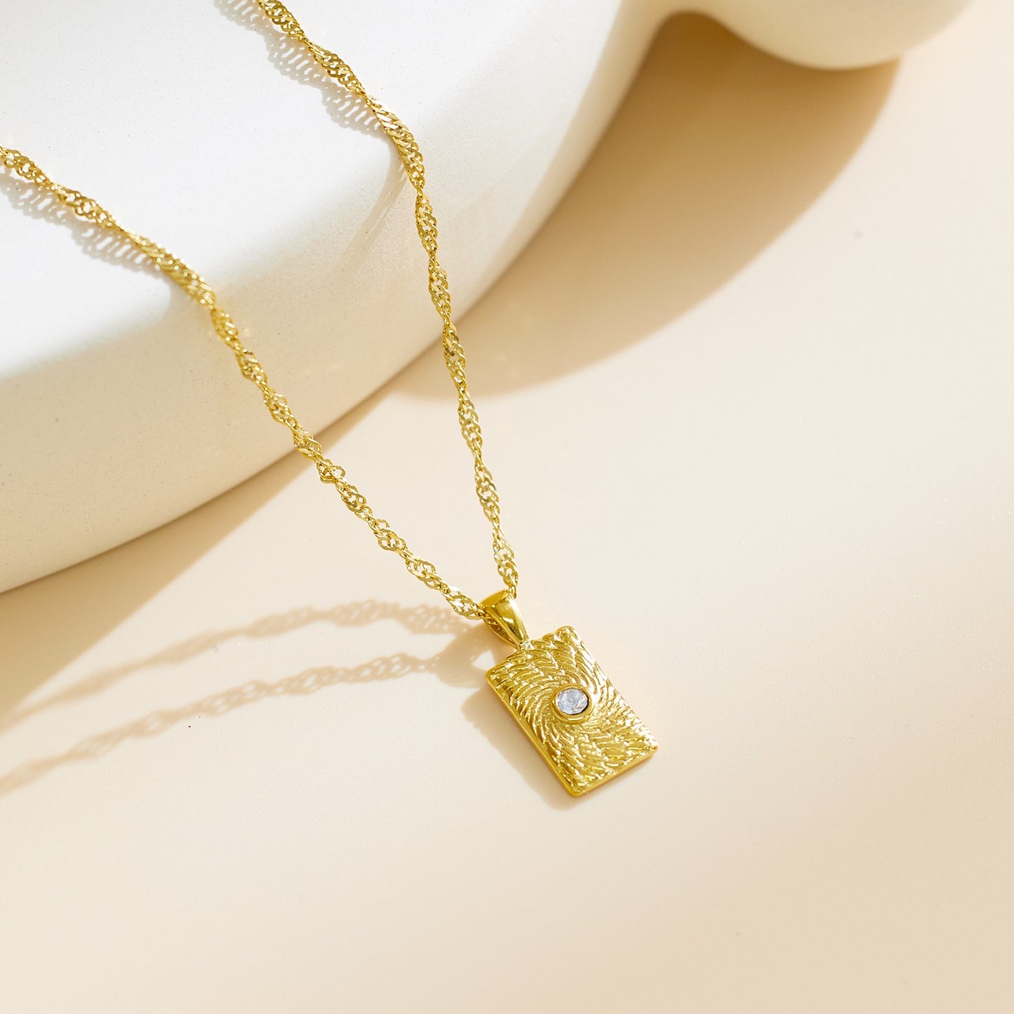 Necklace with rectangular pendant and a stone at the middle.